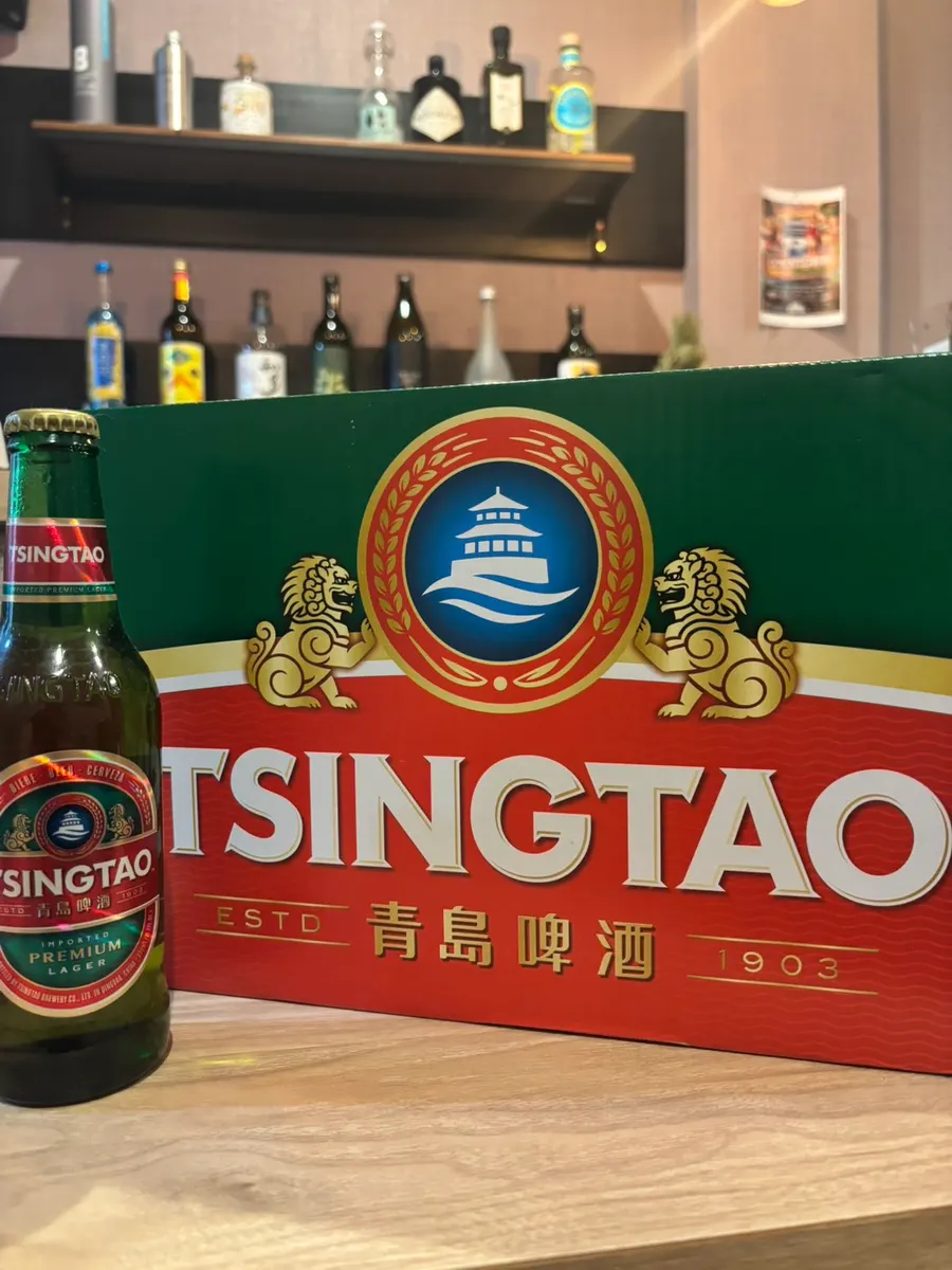 冷えた青島ビールの瓶と、その後ろに置かれた青島ビールのケース